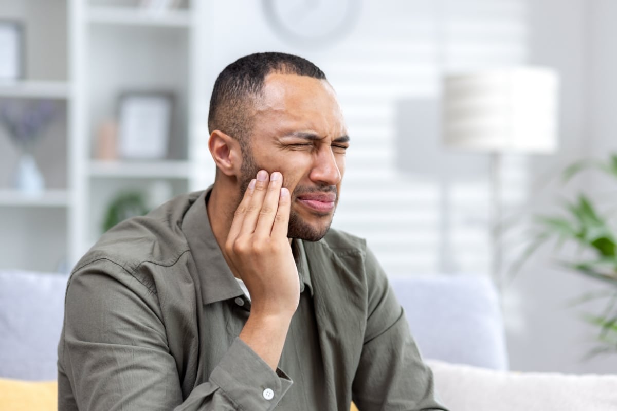 short hair man suffering tooth pain due to TMJ Disorder