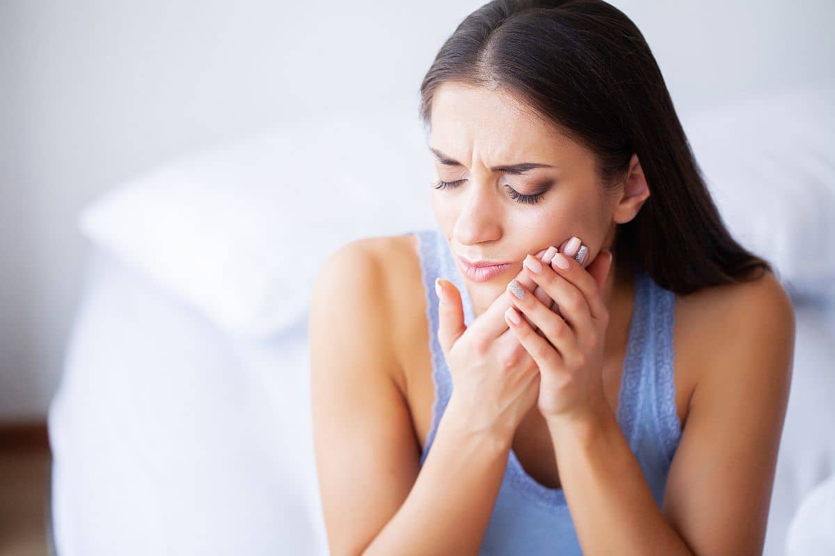 Woman in pain from a toothache or dental injury, holding her face, needing an Emergency Dentist in Phoenix.