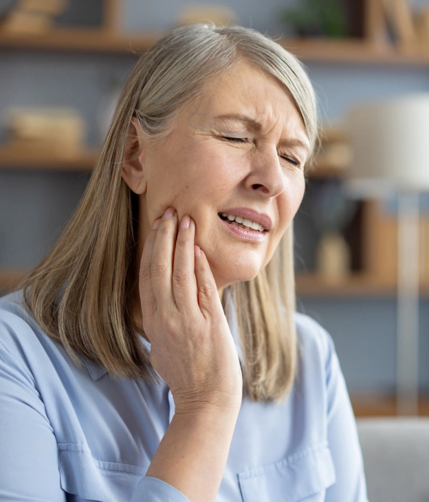 An older woman holding her jaw in pain next to web copy offering fast relief from an emergency dentist at Biltmore Cosmetic & Restorative Dentistry in Phoenix.
