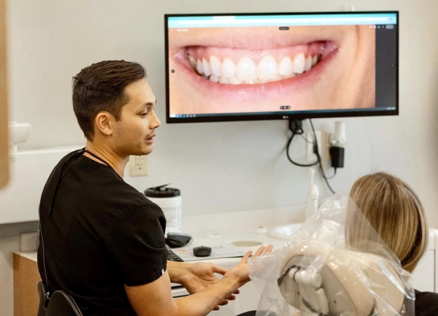 Dr. Brandon Harris reviewing a patient's clear aligner progress on a digital monitor next to text about maintaining Invisalign results in Phoenix.