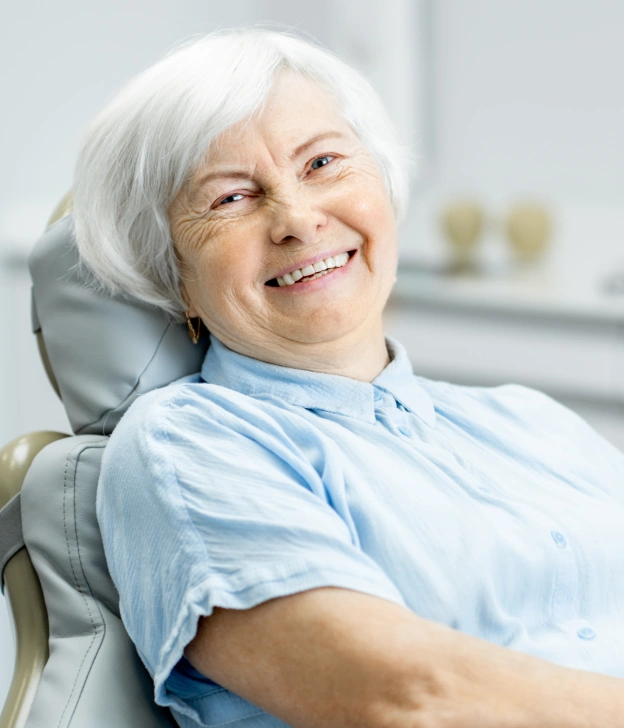A smiling senior woman sitting comfortably in a dental chair next to web copy explaining painless root canal therapy options in Phoenix.